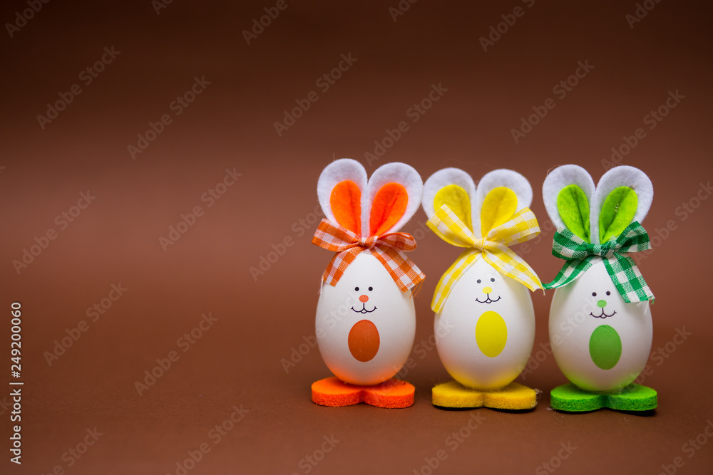 Multicolored funny eggs in form of cute bunny on brown background. Happy easter