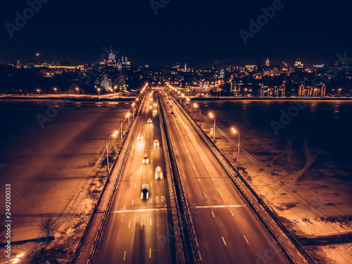 Illuminated bridge with blurred car traffic on night city background, aerial view, drone photo