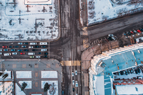 Aerial shot from drone of winter city with snow, roads, cars traffic and buildings top down view © DedMityay