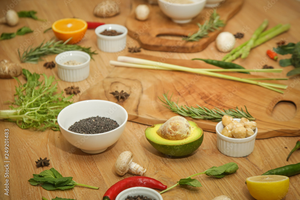 Wooden cutting board surrounded with a variety of herbs, spices, fruits and vegetables Wooden cutting board surrounded with a variety of herbs, spices, fruits and vegetables