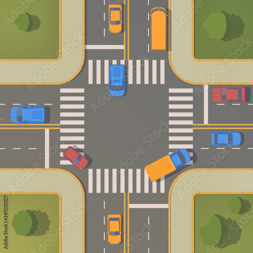 Crossroads of two roads with pedestrian paths, curbs and boards, road markings, grass, bushes and trees.