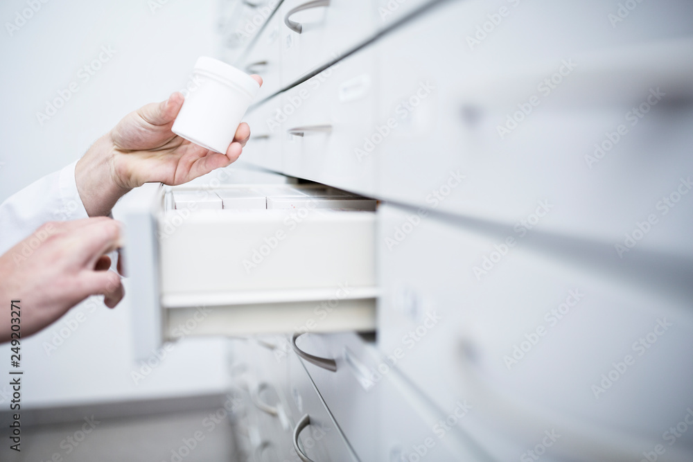 Close-up of pharmacist taking medicine from cabinet in pharmacy Close-up of pharmacist taking medicine from cabinet in pharmacy
