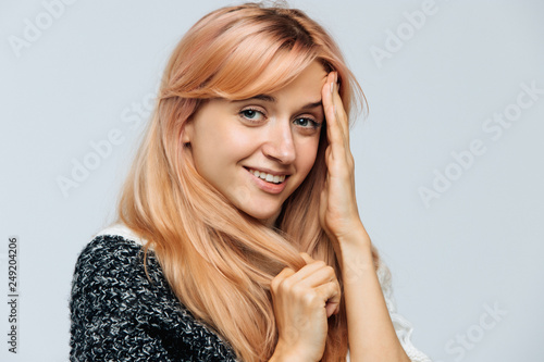 Closeup studio portrait of sincere happy young Caucasian woman with kind eyes  white teeth  perfect skin  blonde strawberry hair  joyful and charming smile isolated on grey background. 