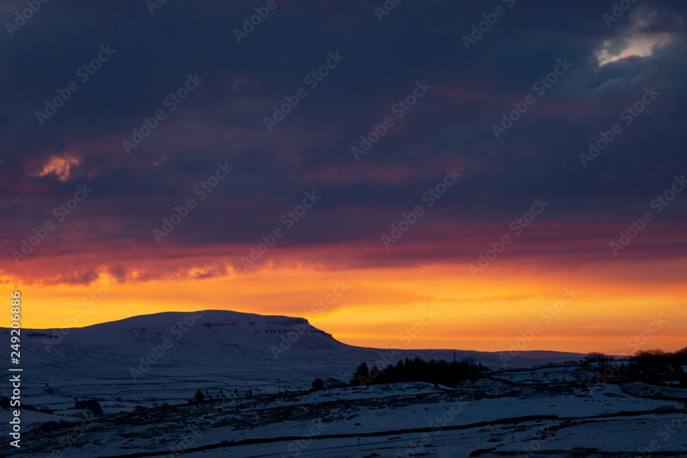 sunrise over penyghent covered in snow