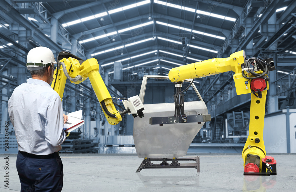 Man hand holding tablet with automate wireless Robot arm in smart factory background. Mixed media of welding robot in the automotive parts industry Man hand holding tablet with automate wireless Robot arm in smart factory background. Mixed media of welding robot in the automotive parts industry