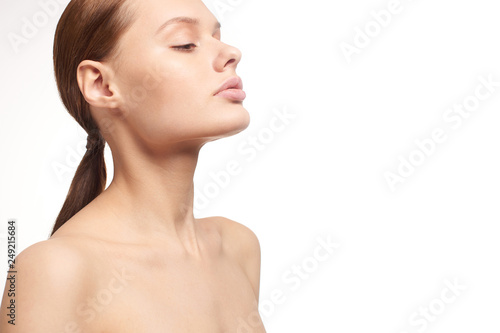 Beauty portrait of young girl with brown hair and big lips on white background with clean face skin and arm near head. Good for cosmetic, medicine and spa . European type