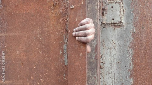 Dirty hand slowly opens rusty metal door photo