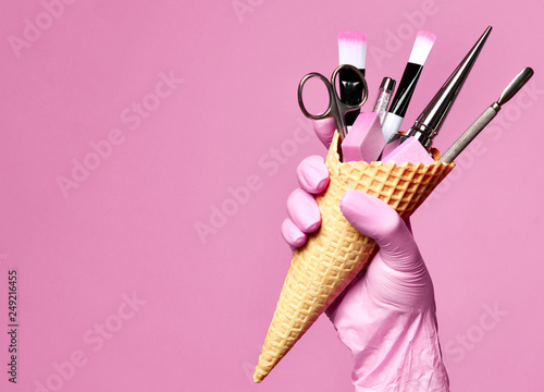Manicure and pedicure abstract concept. Hand hold  waffles cone with instruments for nails salon and spa brush nail file  photo