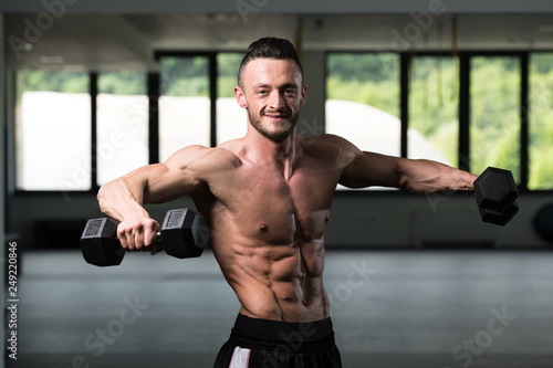 Bodybuilder Exercising Shoulders With Dumbbells © Jale Ibrak
