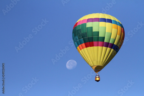 Hot air balloon in flight with moon in the background