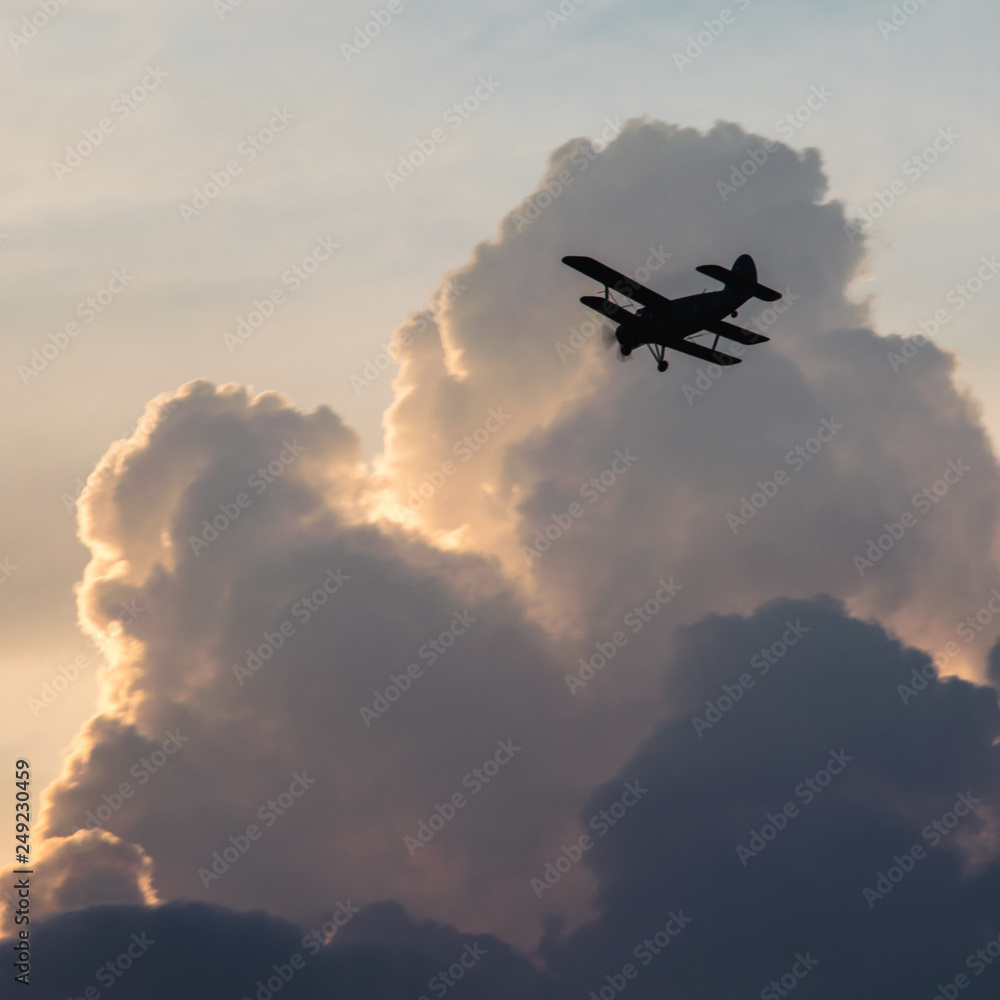 Silhouette of a biplane airplane on a moody heavy cloudy sunset