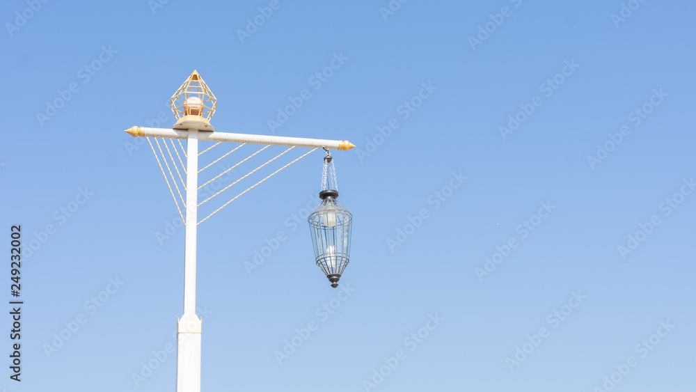 A street light, light pole, lamppost, street lamp,  or lamp standard in blue sky .