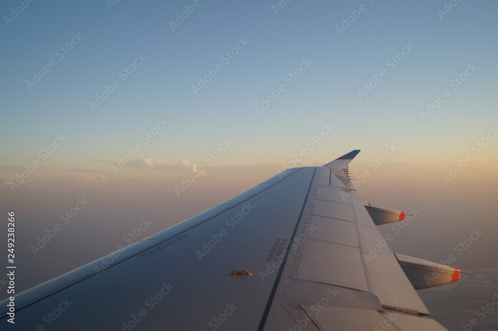 the view from the window of the aircraft, the wing of the aircraft against the sky, sunset the view from the window of the aircraft, the wing of the aircraft against the sky, sunset