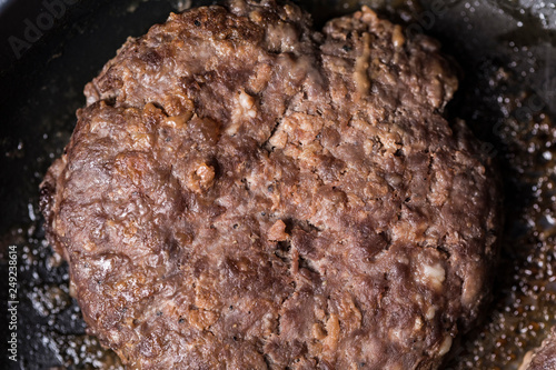 Beef burger being cooked on a black pan photo