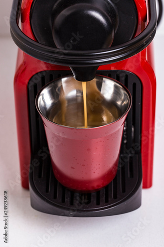 Red coffee machine pouring coffee on a red metal coffee cup