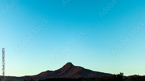 Mountain peak silhouette on a solid blue sunrise sky