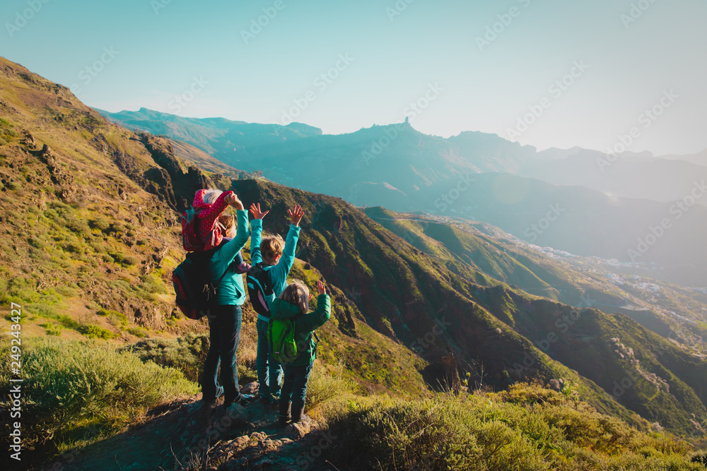 Happy mother with kids travel in sunset mountains, family hiking in nature
