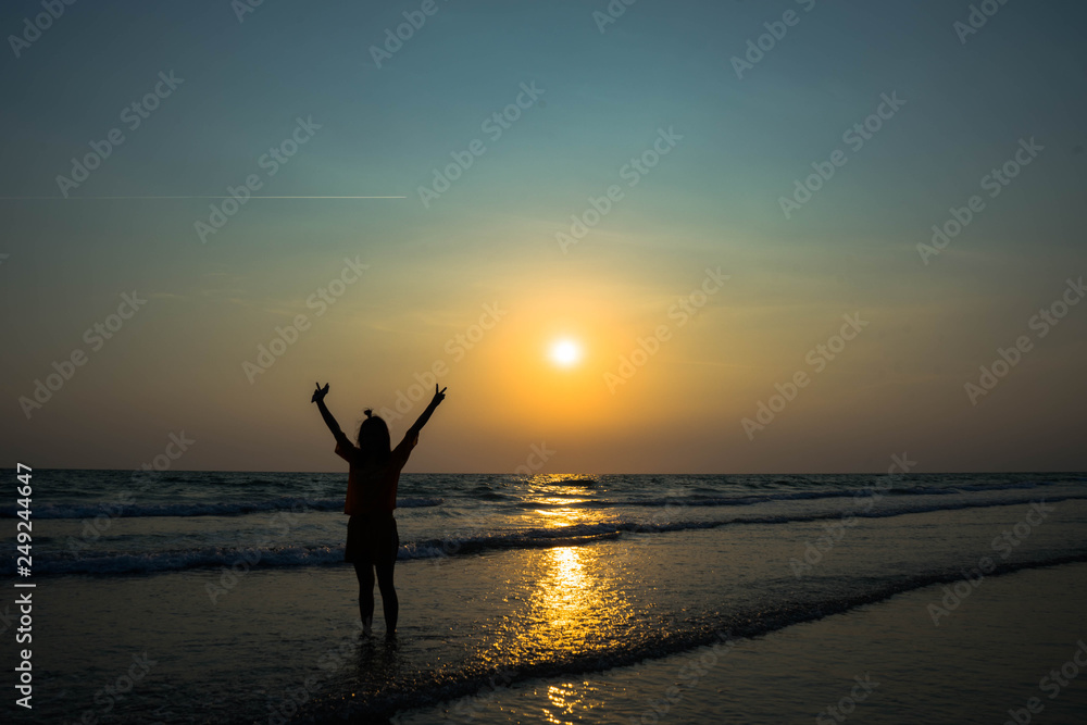 Fototapeta premium silhouette of woman on the beach at sunset