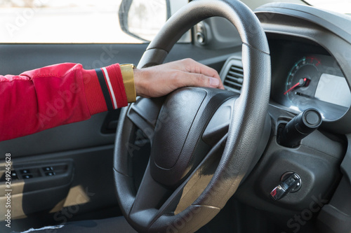 men's hand with a watch on the steering wheel of a modern car
