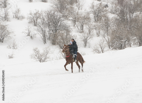 a man with a child on a horse in the winter mountains