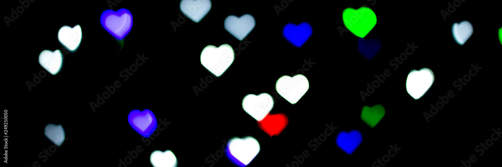 Multicolored bokeh on black background. Heart shape. Love Concept, Valentine's Day. Can be used as a background or wallpaper. Banner.