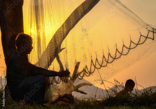 Fisherman repairing fishing net at sunset. photo