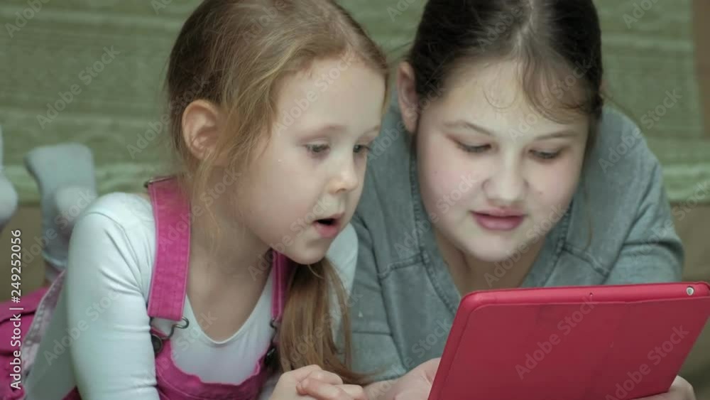 girls sisters playing on the tablet in the room, web surfing, rest girls sisters playing on the tablet in the room, web surfing, rest