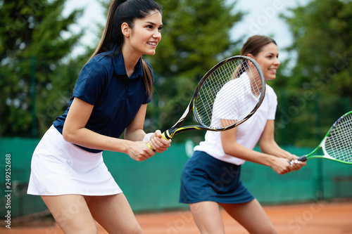 Young happy fit women playing tennis on tennis court © NDABCREATIVITY