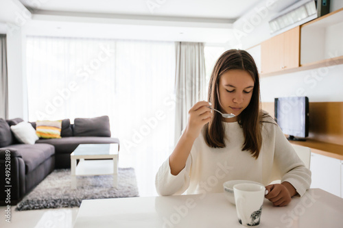 Teenage girl eating brekfast in living room