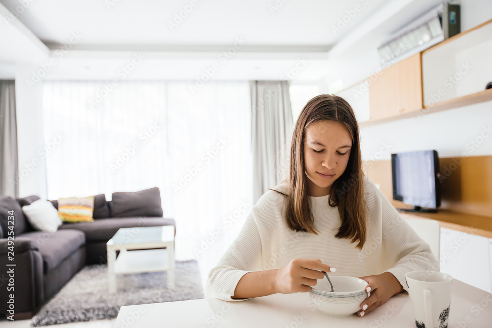 Teenage girl eating brekfast in living room Teenage girl eating brekfast in living room