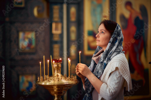 Orthodox woman praying in front of icons in the Church