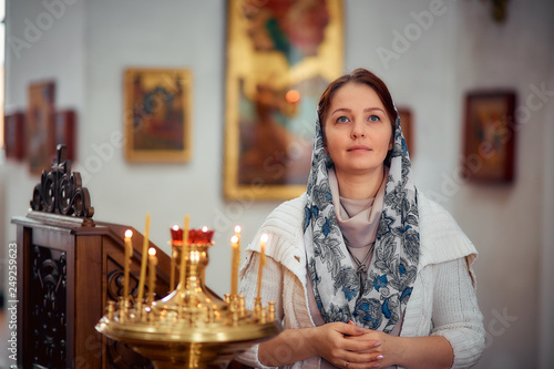 Billede på lærred lifestyle woman lights candles in the Church, praying in front of the icon
