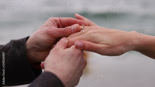 Close-up senior female hand getting engagment ring on her finger from elderly boyfriend. Senior male making marriage proposal to fiancee outdoors. Female looking and admiring her diamond ring slow mo