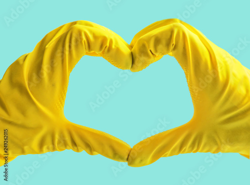 Getting started cleaning. Yellow rubber gloves for cleaning on blue background .General or regular cleanup. Commercial cleaning company. Copy space.Hands in yellow rubber gloves making heart shape
