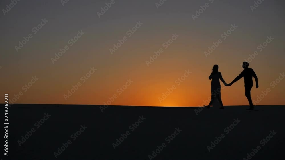 Man and woman pose embracing in morning sand desert closeup of heads and legs. Couple in love stand together in aura of sun holding each other. Man and woman pose embracing in morning sand desert closeup of heads and legs. Couple in love stand together in aura of sun holding each other.