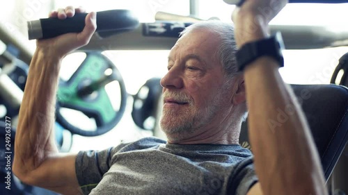 A senior man doing strength workout exercise in gym. photo