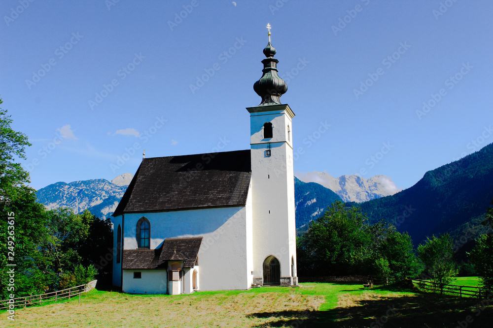 a church on a hill in front of the Alps
