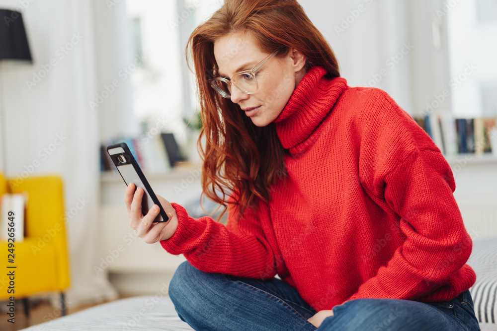 Young woman reading her mobile in consternation Young woman reading her mobile in consternation