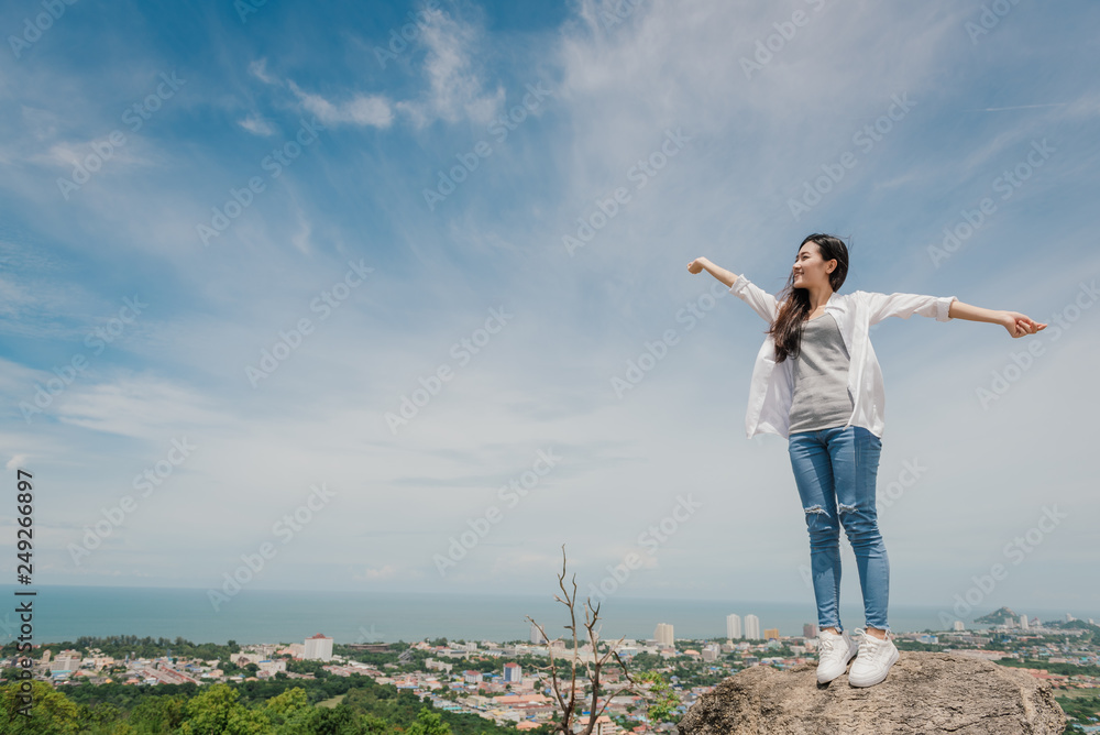 Portrait of carefree happy asian woman standing on top of mountain edge cliff enjoying on her face. Freedom; Lifestyle; Enjoyment; Relaxing in mountains at Huahin in Thailand. Portrait of carefree happy asian woman standing on top of mountain edge cliff enjoying on her face. Freedom; Lifestyle; Enjoyment; Relaxing in mountains at Huahin in Thailand.