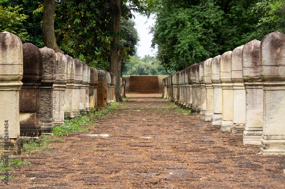 Laterite stone paved walkway with stone posts to the gates of ancient Khmer temple Prasat Sdok Kok Thom in Sa Kaeo province of Thailand Laterite stone paved walkway with stone posts to the gates of ancient Khmer temple Prasat Sdok Kok Thom in Sa Kaeo province of Thailand