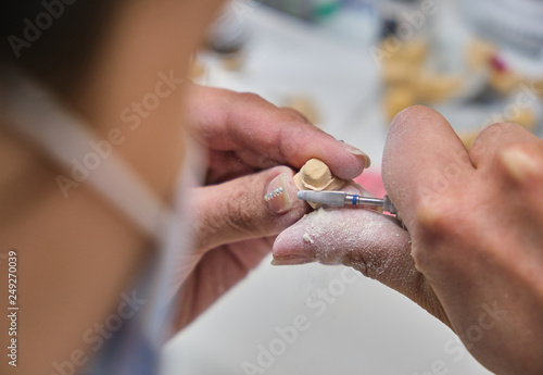 Dental technician using a brush with ceramic dental implants in his laboratory