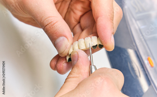 Dental technician or dentist working with tooth dentures in his laborator