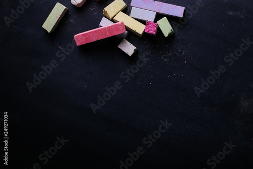 Multicolored crayons lie on a black chalkboard, copy space. The concept of school, education and childhood. photo