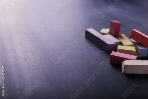 Multicolored crayons lie on a black chalkboard, copy space. The concept of school, education and childhood. photo