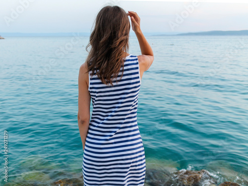 girl standing on the shore and looking at the sea