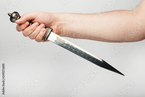 Male hand holds an old roman dagger