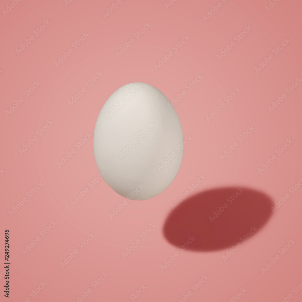 White egg in the air with a shadow, on a colored background. Morning mood. White egg in the air with a shadow, on a colored background. Morning mood.