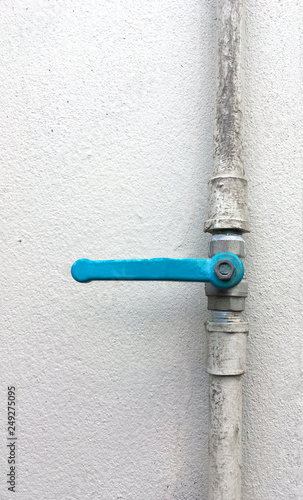 water PVC pipe with blue valve on white concrete wall background