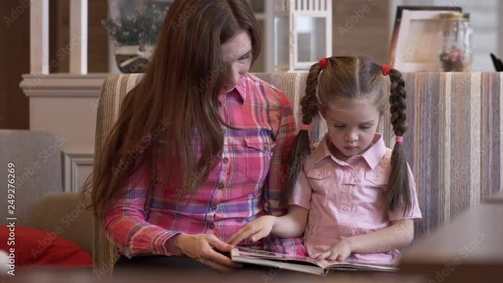 Charming Young Mother And A Pretty Daughter Flipping Through The Menu Charming Young Mother And A Pretty Daughter Flipping Through The Menu