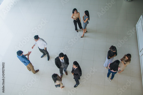 Asian office workers stand and talk in the office lobby. © Nawarit